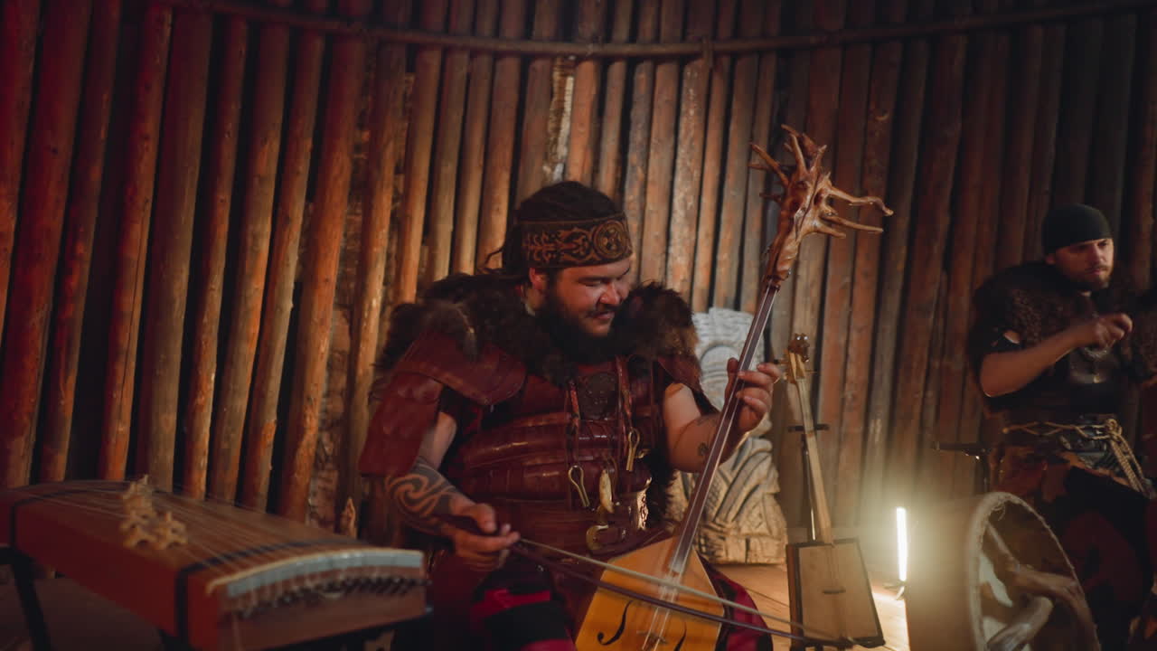 Man in Altai clothes plays bow instrument with drummer