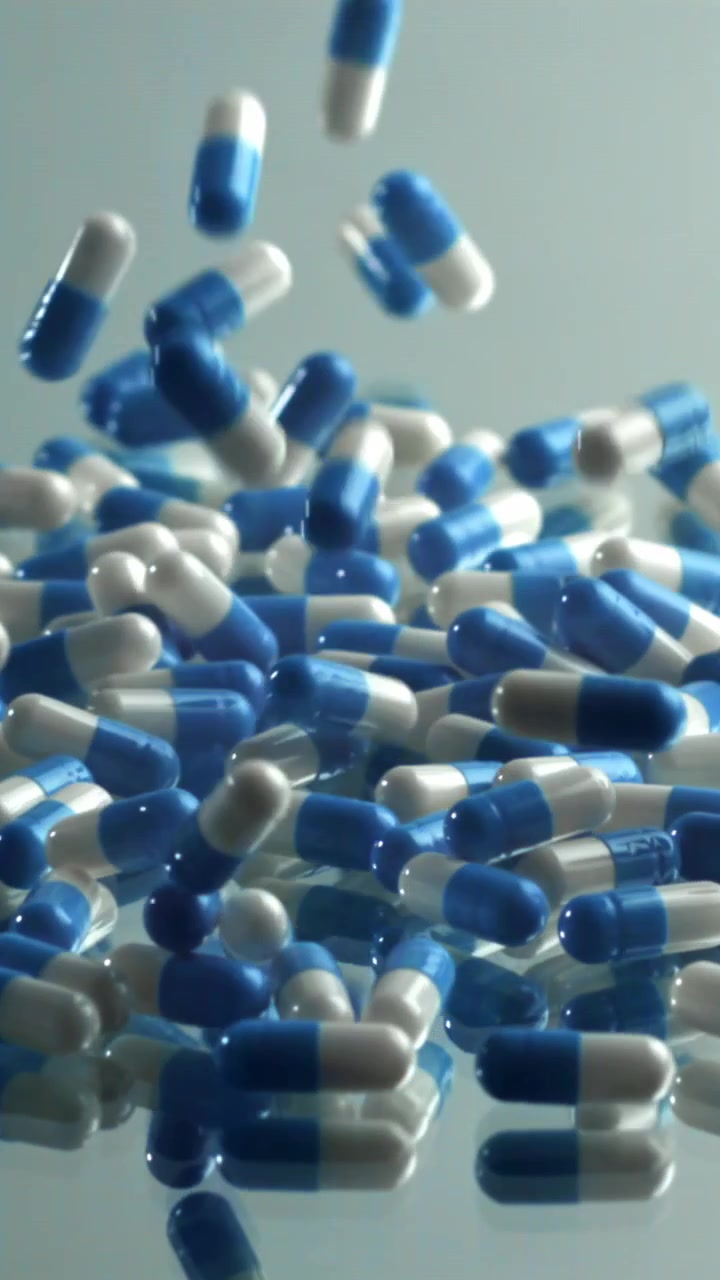 Movimento rallentato di capsule farmaceutiche blu e bianche che cadono