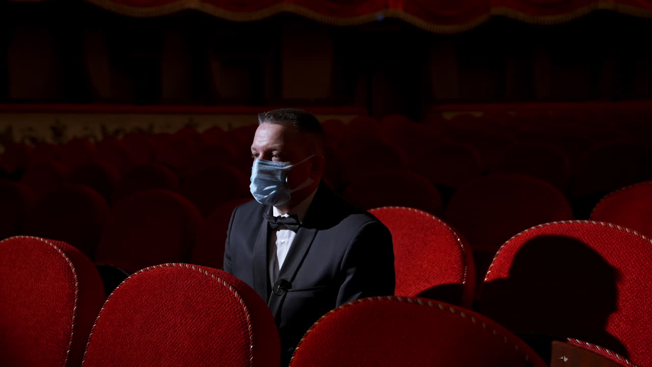 Man in theatre with protection mask. Man wearing face protective medical masks for protection from virus
