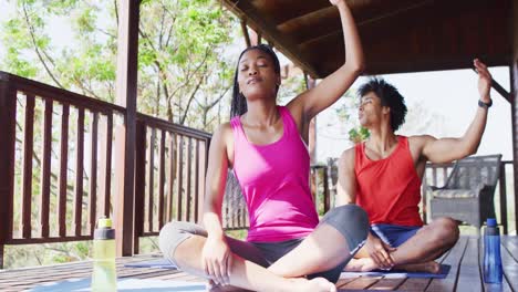 happy african american couple doing yoga and stretching in log cabin, slow motion