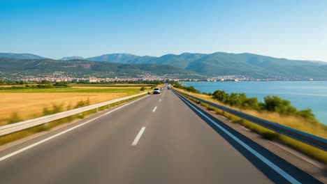 scenic highway drive along the sea with mountains and a distant city