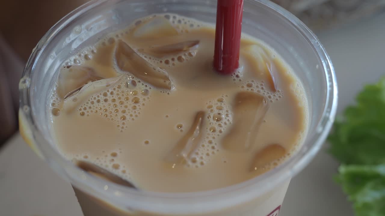 Primo piano di un caffè freddo con una cannuccia rossa.