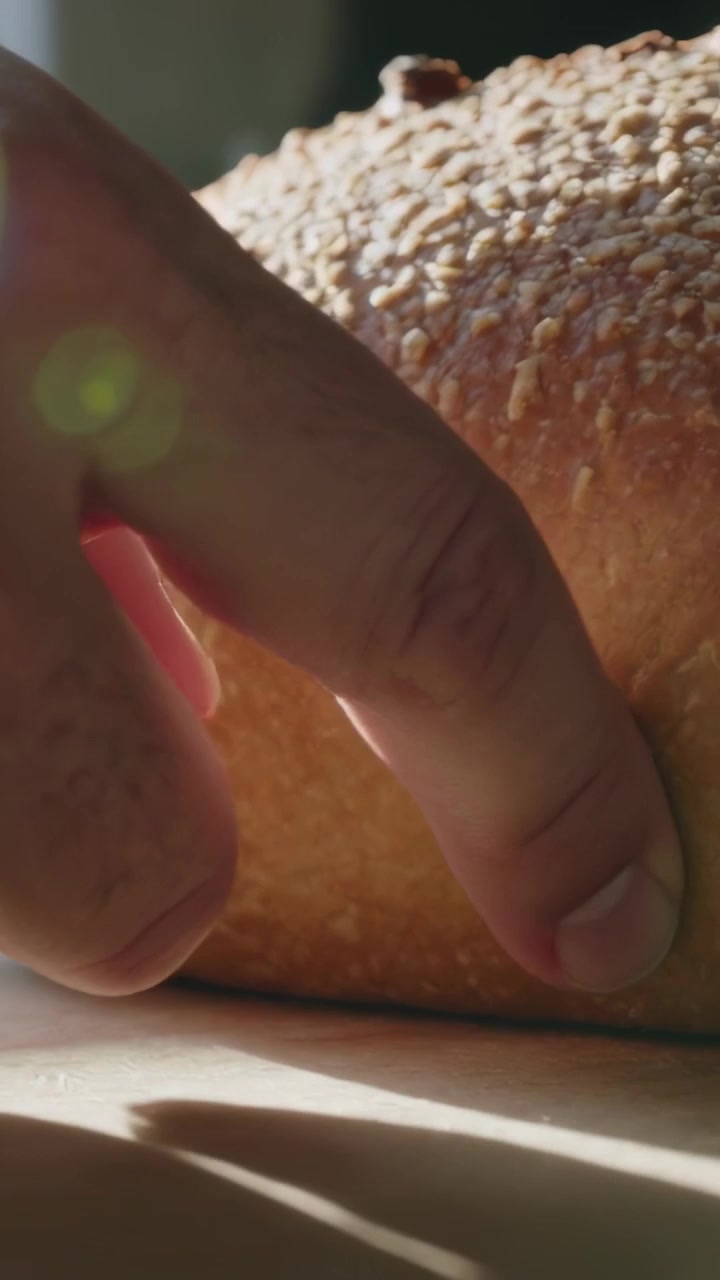 Vertical video: Pressing index finger testing crusty loaf on wooden board at home, checking texture