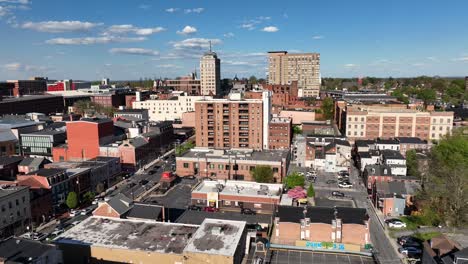 Aerial-flyover-solar-panels-on-roof-of-red-brick-factory-and-cityscape-during-sunny-day