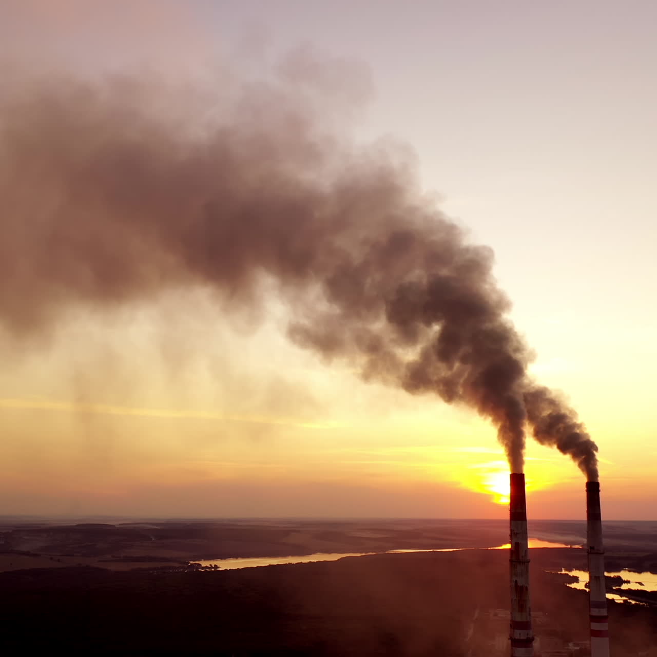 Industrial landscape. Smoke from pipes of the power plant at sunset. Environmental pollution.