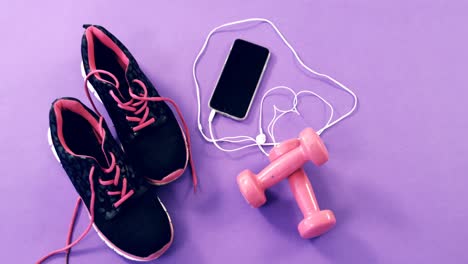 mobile phone with headphones, shoes and dumbbells on table