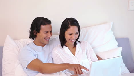 en una cama usando una pareja de portátiles