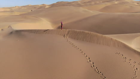 drone circling around a woman holding a blanket in the air in the sahara desert.