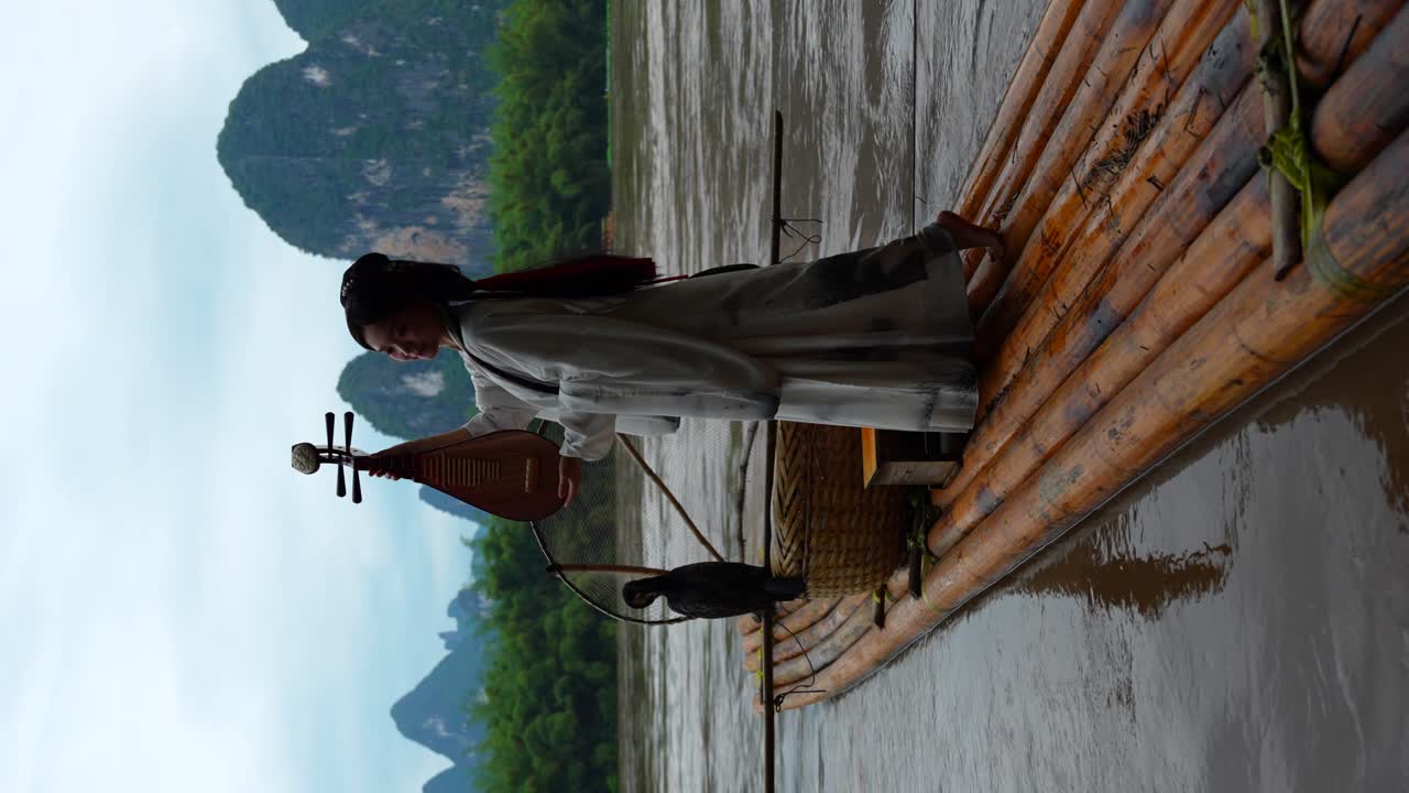 Vertical shot of a barefoot girl in Hanfu clothing holding a pipa on a bamboo raft for a photo session