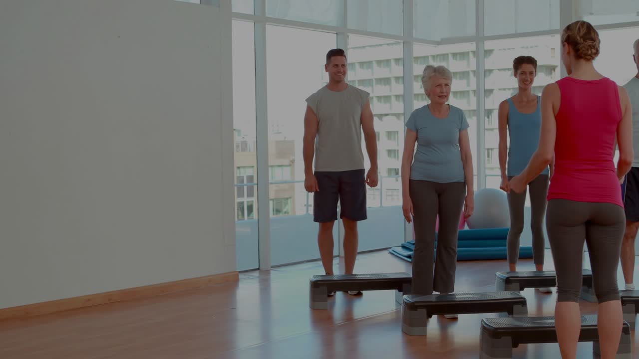 Instructor cueing and leading class stepping on steps while animated charts overlaying fitness data