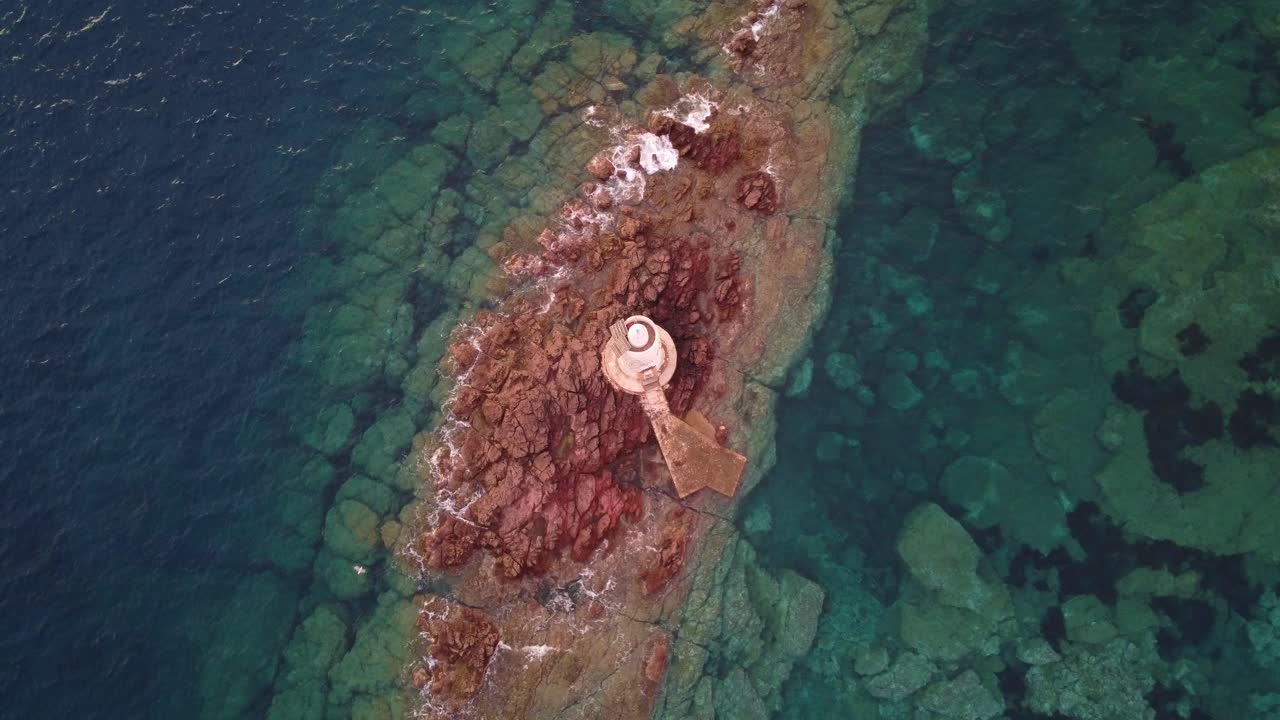 해안 바위에 있는 작고 외로운 등대의 하향식 공중 전망, 축소