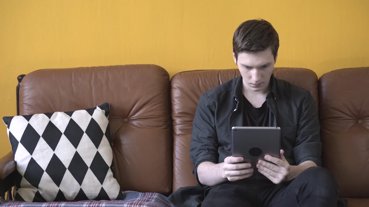 joven usando la tableta en el sofá