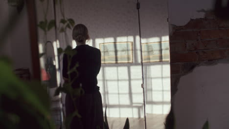 woman in a sunlit room with artwork and mirror
