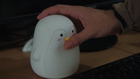 close-up shot of cute penguin night light turning on at student's desk.
