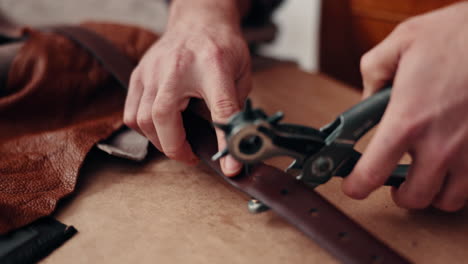 hands, leather factory and hole punch for belt