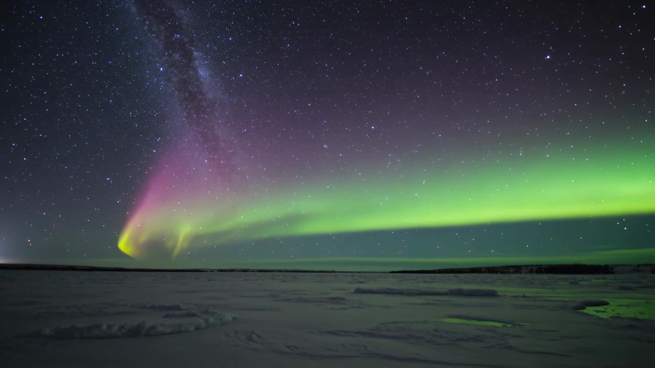Arco aurorale luminoso che si estende su una pianura di neve e ghiaccio dal vento solare, Via Lattea e pozza riflettente.