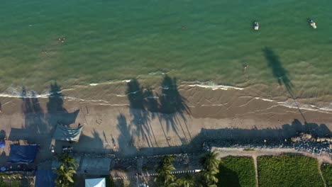 bird's eye aerial drone shot of the tropical bessa beach in the capital city of joao pessoa, paraiba, brazil with people enjoying the ocean surrounded by palm trees, beach houses, and fishing boats