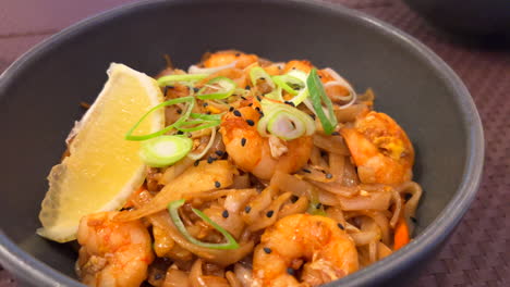 traditional pad thai wok noodles with shrimps, spring onion and a lemon slice, thai restaurant, delicious asian food, 4k shot