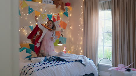 niña feliz saltando en la cama vistiendo disfraz jugando a un juego disfrutando de la imaginación juguetona en un dormitorio colorido en casa