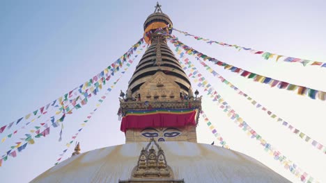 swayambhunath stupa with prayer flags swaying on the wind against the clear blue sky in kathmandu, nepa