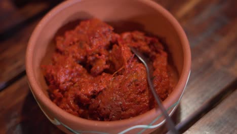 Ajvar-in-earth-jar-with-little-spoon-on-a-wooden-desk