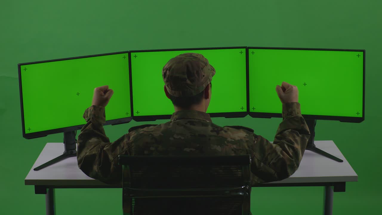 Back View Of Happy Asian Man Soldier Celebrating And Dancing While Working With Mock Up Multiple Computer Monitor In Green Screen Studio