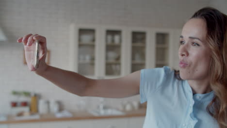 hermosa chica posando para la cámara del teléfono en el interior de la cocina. mujer haciendo selfie.
