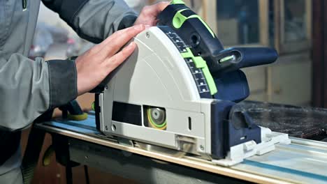 close-up of a carpenter's hand working with hand circular saw in a home workshop
