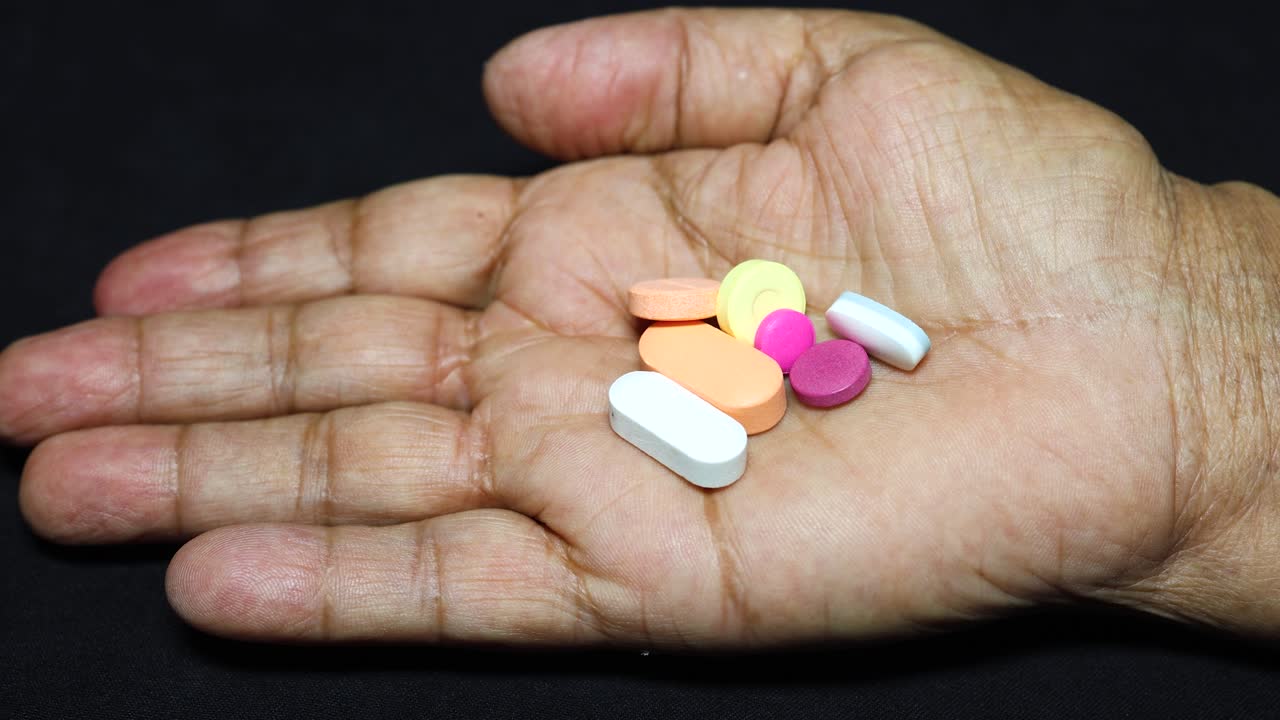 old age palm holding pills with black background