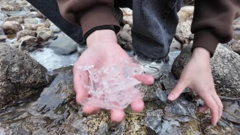 Manos-Recogiendo-Fragmentos-De-Hielo-De-Un-Río-Congelado,-Creando-Una-Atmósfera-De-Naturaleza-Invernal-Y-Tranquilidad