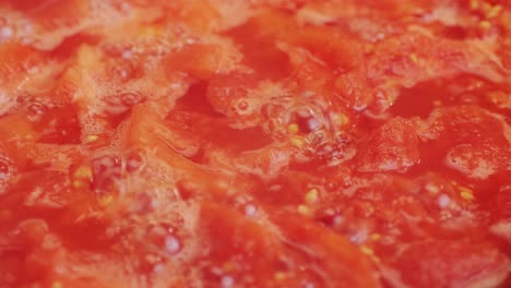 cooking fresh peeled canned tomato juice sauce in pan, peeled tomatoes boiling in their own juice, making tomatoes pasta sauce .top view close up, italian traditional cuisine food.