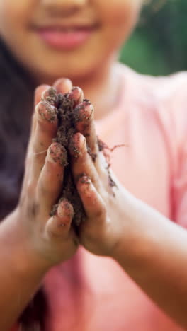 girl rubbing mud on her hands