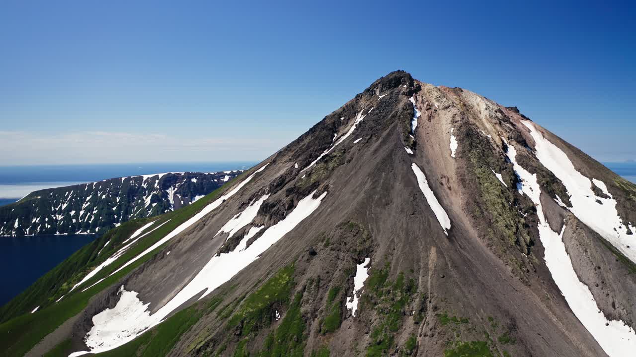 удивительная панорама с воздуха. снежный зеленый пик вулкана на солнце, чистое голубое небо