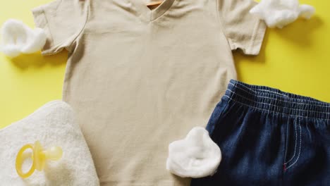 video of close up of baby girl outfit with shirt, denim skirt and dummy on yellow background