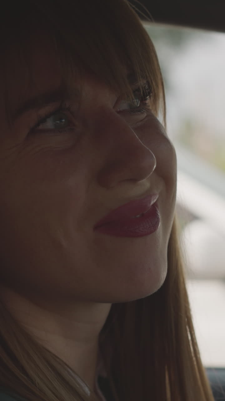 Disgruntled businesswoman grumbles looking out car windows. Long-haired female driver sits in vehicle feeling sad to get stuck in traffic jam closeup