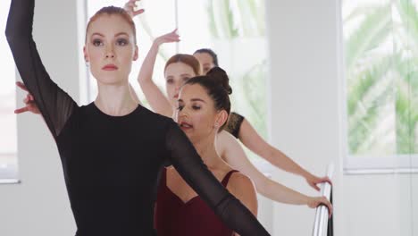 caucasian ballet female dancers exercising with a barre by a mirror during a ballet class