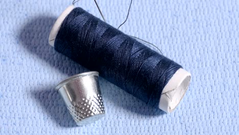 spool with needle and thimble on cloth