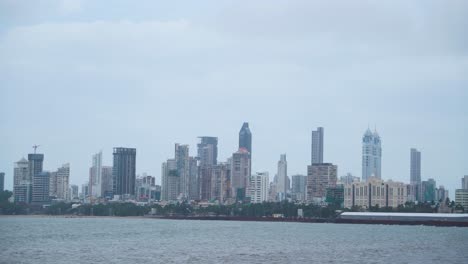 pan shot of skyline buildings and skyscrapers of mumbai with ocean in front on a cloudy monsoon day