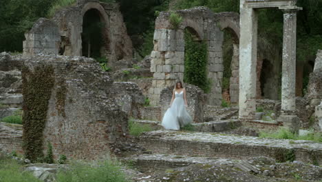 woman in white dress walking through ancient stone ruins