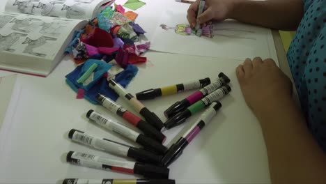 diseñadora de moda latina esbozando nuevas ideas para vestidos usando marcadores de color