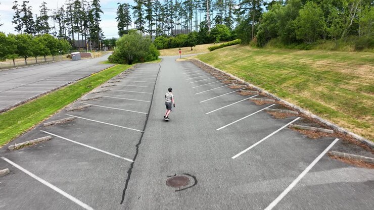 Aerial of an adult male riding a One Wheel through an empty parking lot