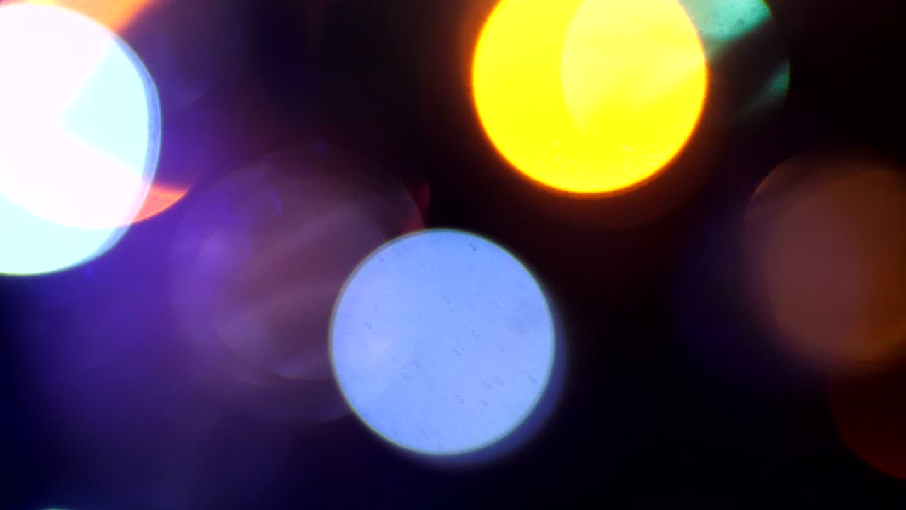 fondo de navidad. luces borrosas de una guirnalda de año nuevo. bombillas de color azul y naranja parpadeando en un telón de fondo oscuro fuera de foco 50 fps 4k