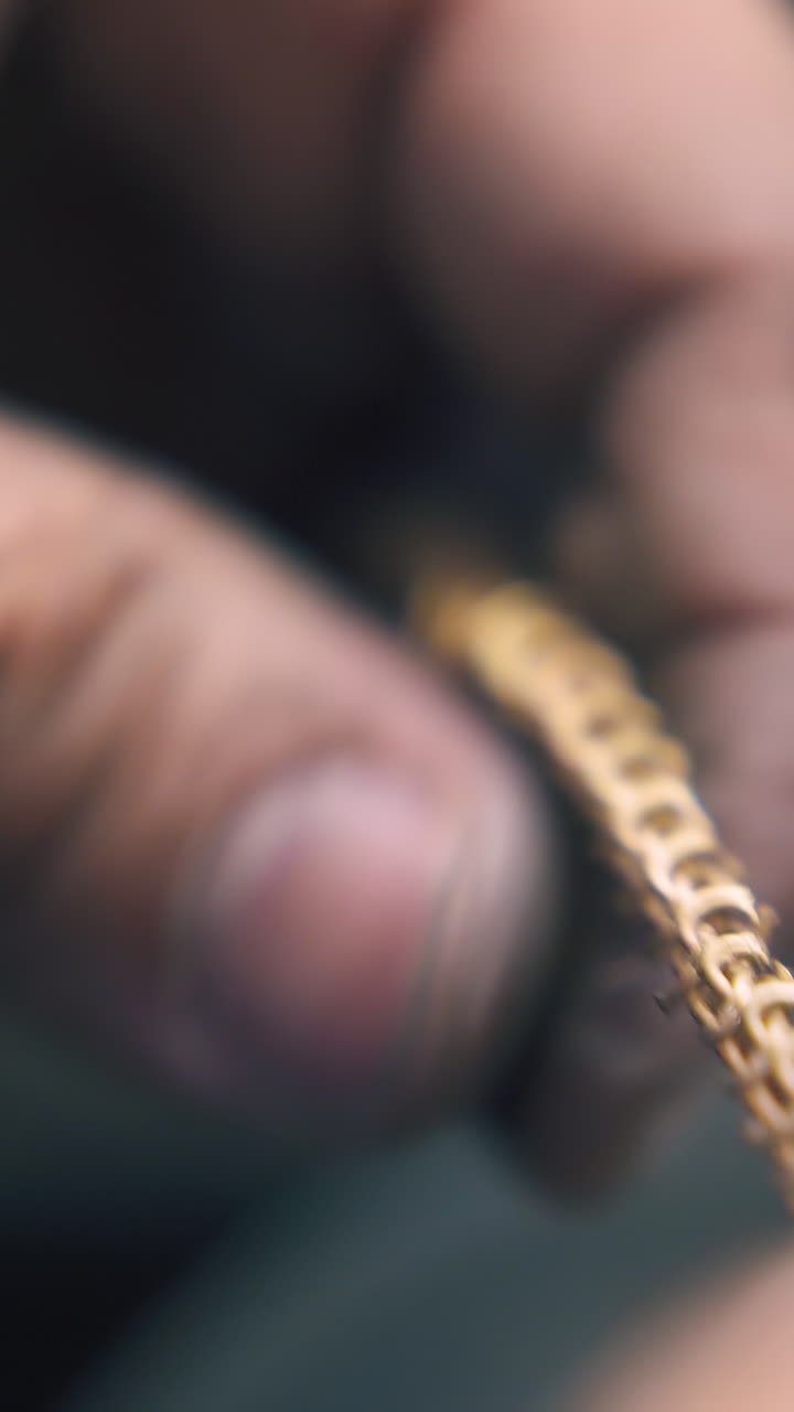 CU: skilled jeweler removes leftovers from new shiny chain with vintage cutting pliers on blurred background extreme closeup