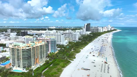 Magníficas-Imágenes-Aéreas-De-Drones-De-Una-Playa-De-Arena-En-Miami,-EE.-UU.,-Movimiento-Lento-Hacia-Adelante-Que-Revela-Un-Hermoso-Paisaje-Marino,-Con-Gente-Relajándose-Y-Edificios-Altos