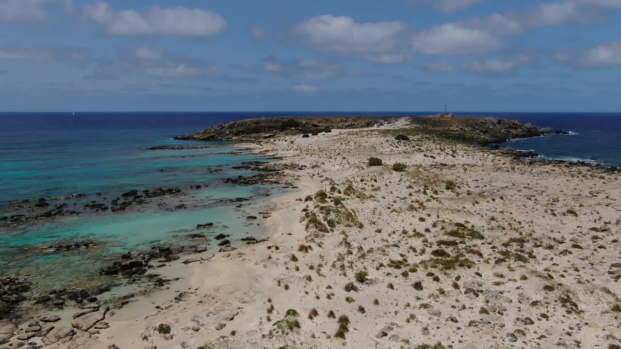 península de elafonissi de creta grecia con la iglesia de agia irini a la derecha y la cueva de la memoria a la izquierda, dolly aéreo en tiro