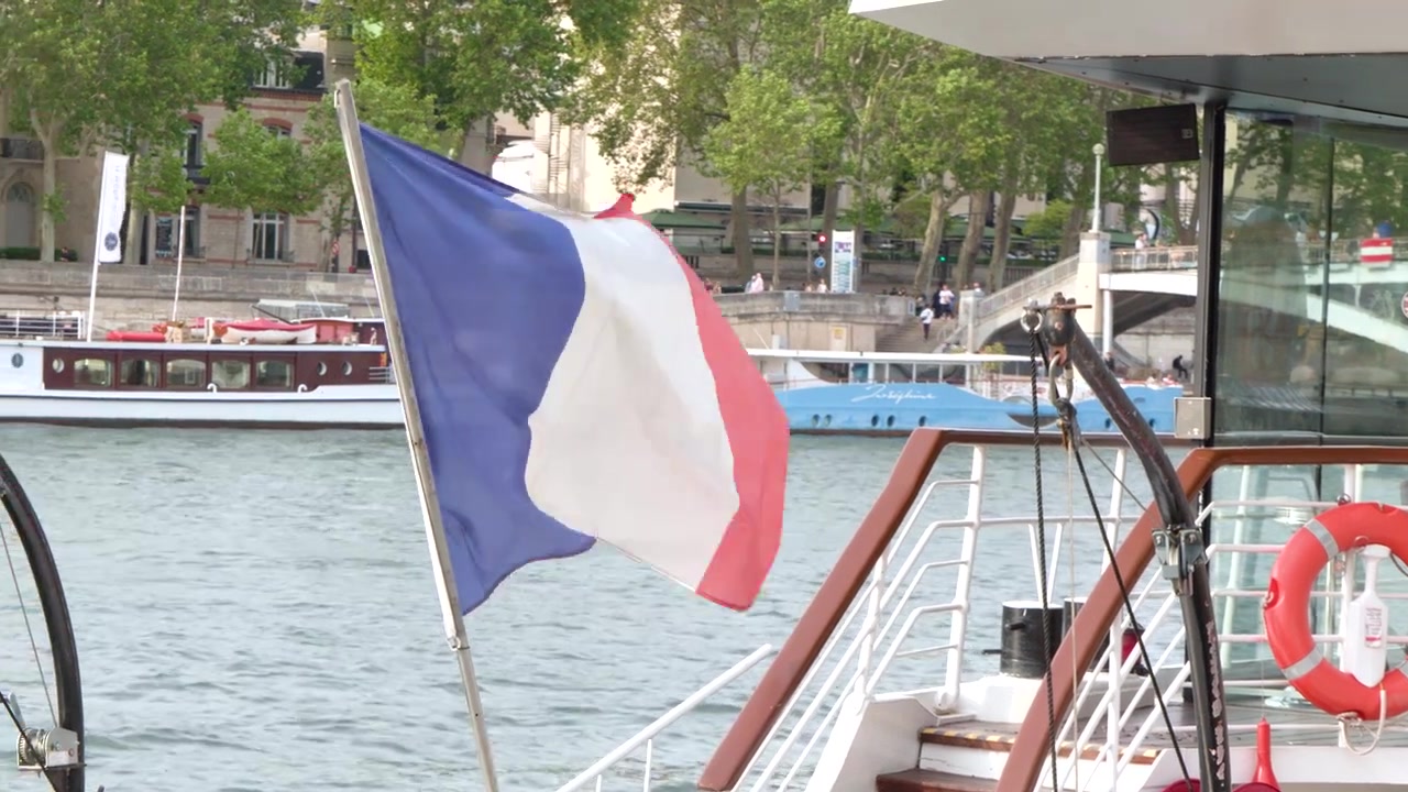 Una bandiera tricolore francese sventola da una barca da crociera che naviga lungo la Senna a Parigi.