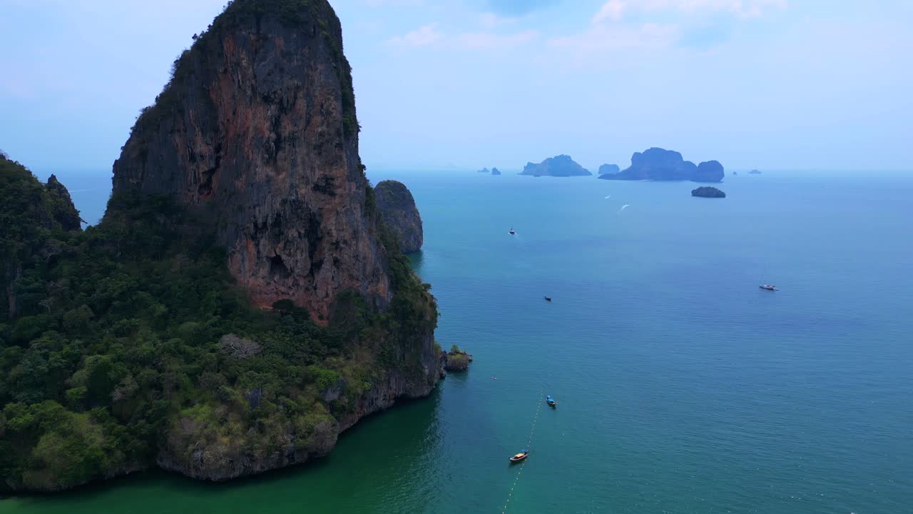 Railay Beach, showcasing its famous limestone cliffs, lush greenery, and the vibrant turquoise waters of the Andaman Sea. drone shot footage from above
