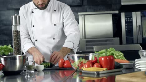 chef cocinando ensalada fresca en la cocina. manos masculinas cortando pepino.