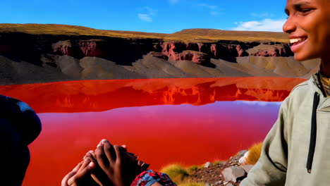children by a red lake in a volcanic landscape