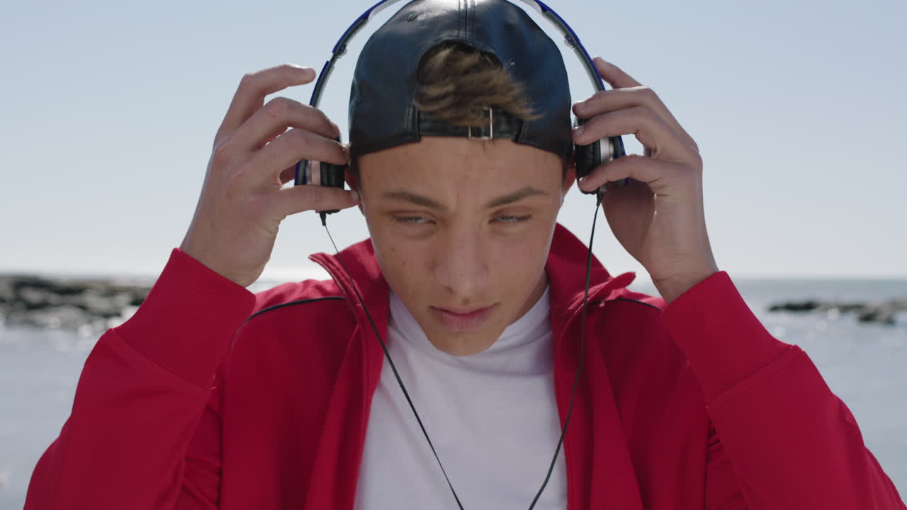 retrato de un chico tranquilo y confiado en la playa con auriculares escuchando música